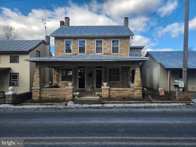 view of front of house with a standing seam roof, metal roof, a chimney, and covered porch