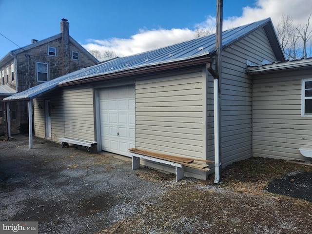 view of property exterior with an attached garage and metal roof