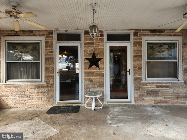 doorway to property with brick siding and a ceiling fan