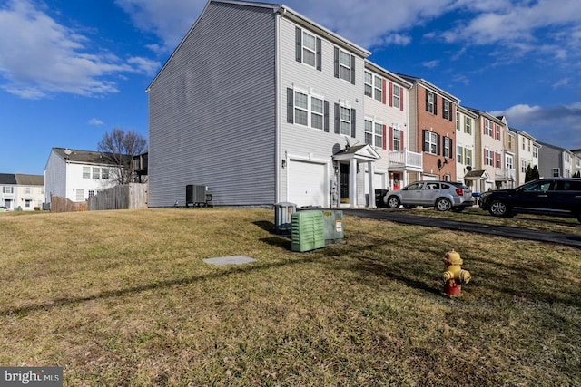 view of home's exterior with a garage, a residential view, a yard, and central air condition unit