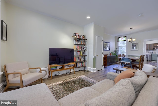 living area with wood finished floors, recessed lighting, crown molding, baseboards, and a chandelier