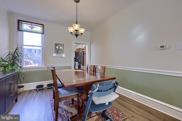 dining room featuring a chandelier, wood finished floors, baseboards, and ornamental molding