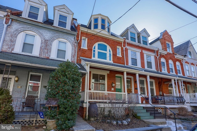 townhome / multi-family property with brick siding and covered porch