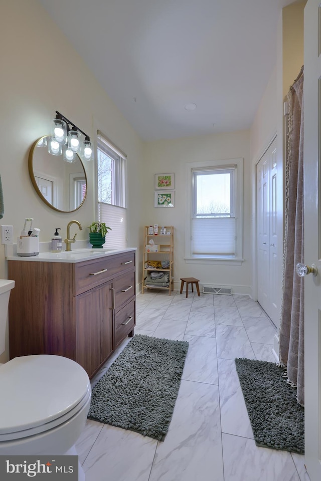 bathroom featuring plenty of natural light, marble finish floor, toilet, and visible vents