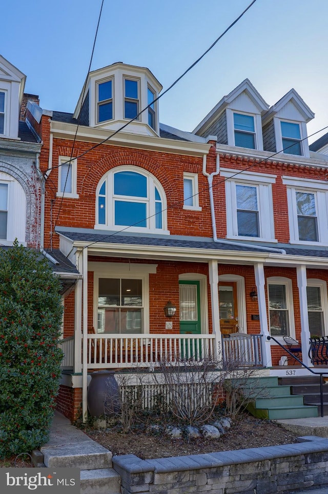 view of front of home with brick siding and a porch