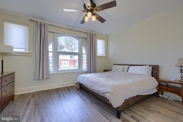 bedroom with ceiling fan, baseboards, wood finished floors, and ornamental molding