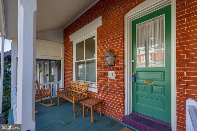 entrance to property featuring brick siding and covered porch