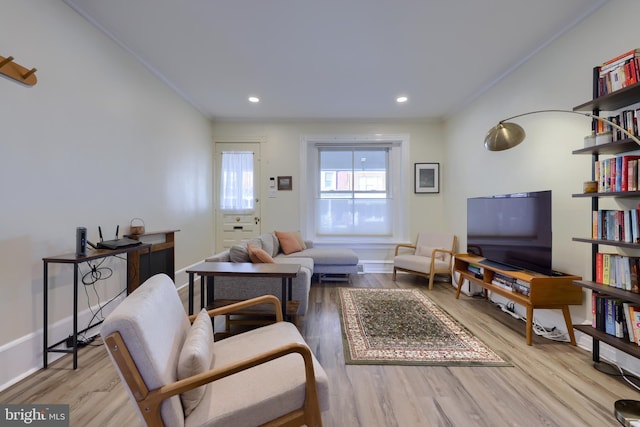 living area with ornamental molding, baseboards, and wood finished floors