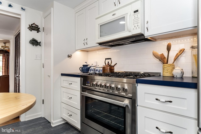 kitchen with tasteful backsplash, white cabinets, dark countertops, white microwave, and high end stainless steel range oven