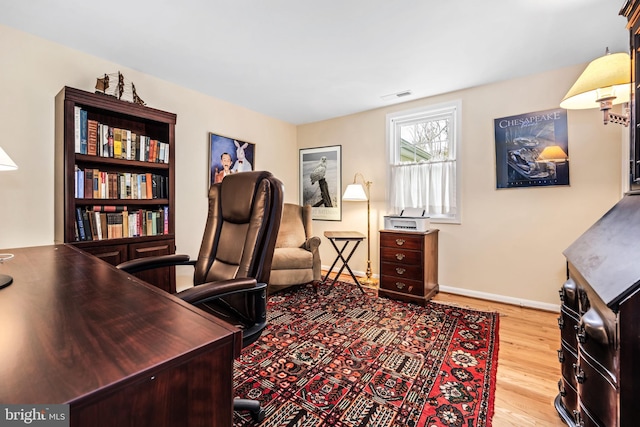 office area featuring baseboards, visible vents, and wood finished floors