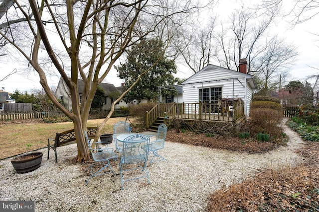 rear view of house with a chimney, fence, and a deck