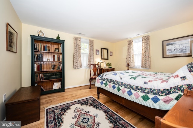 bedroom with visible vents, multiple windows, light wood-style flooring, and baseboards