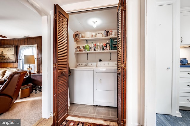 clothes washing area featuring visible vents, a ceiling fan, washing machine and dryer, wood walls, and laundry area