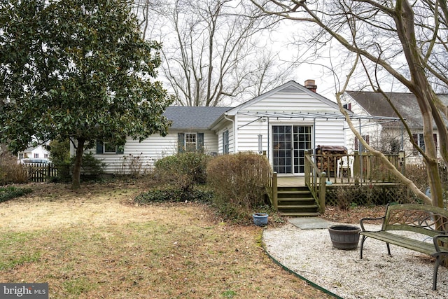 rear view of house with an outdoor fire pit, a chimney, a deck, and a shingled roof