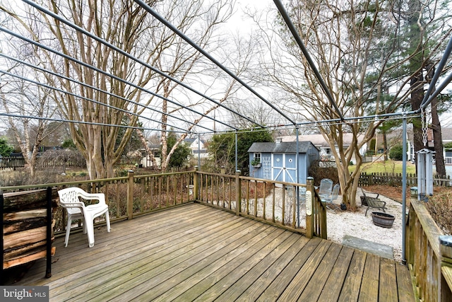 deck with a shed, a fire pit, and an outdoor structure