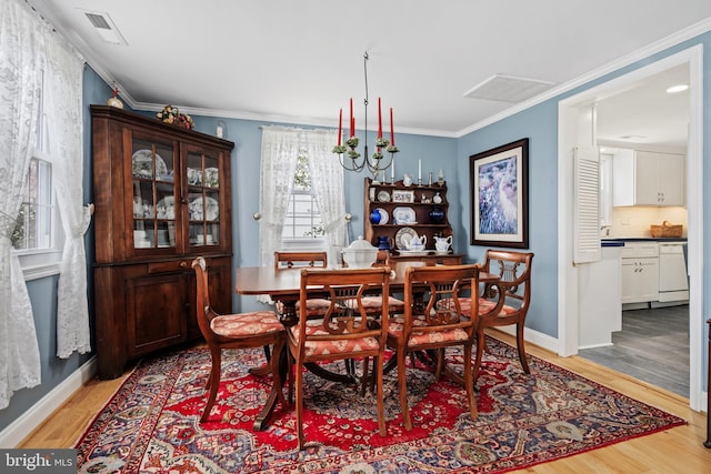 dining space featuring light wood finished floors, visible vents, and crown molding