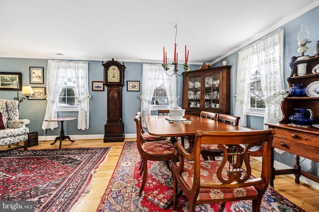 dining room with ornamental molding, a healthy amount of sunlight, and light wood-style flooring