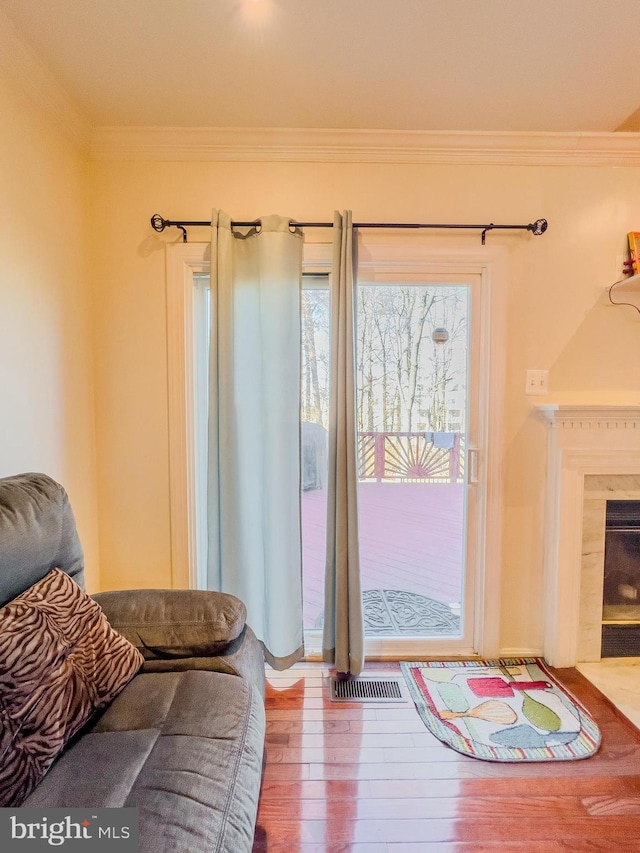 entryway featuring a fireplace with flush hearth, visible vents, wood finished floors, and ornamental molding