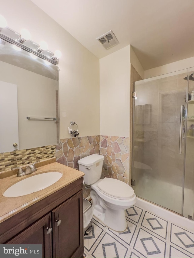 bathroom featuring a stall shower, visible vents, tile walls, and toilet