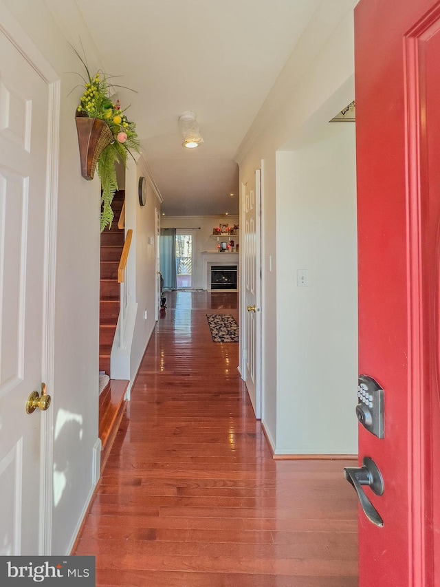 corridor featuring wood finished floors, baseboards, and stairs