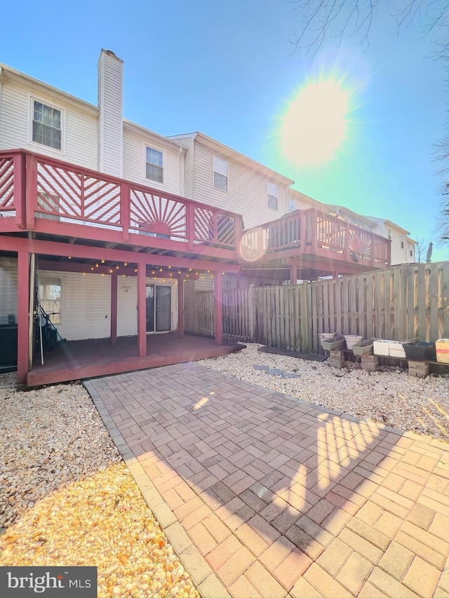 back of house featuring a patio, a chimney, and fence