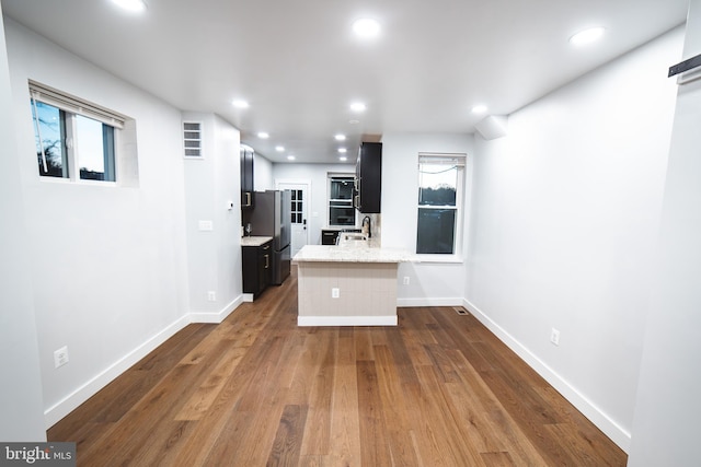 kitchen featuring dark cabinets, recessed lighting, a sink, and freestanding refrigerator