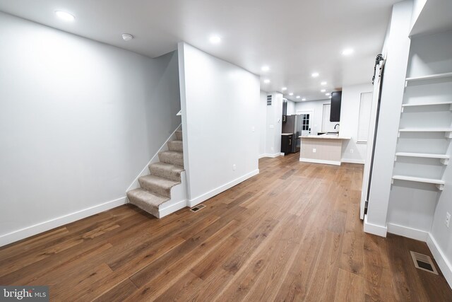 unfurnished living room with recessed lighting, visible vents, baseboards, and wood finished floors