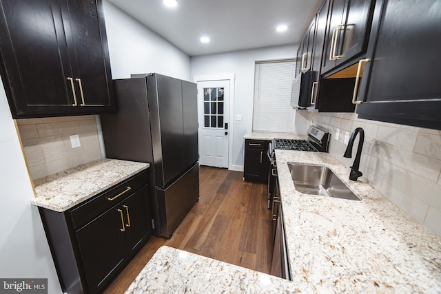 kitchen with light stone counters, dark wood finished floors, dark cabinetry, and freestanding refrigerator