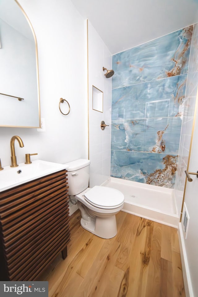 bathroom with toilet, a stall shower, wood finished floors, and vanity