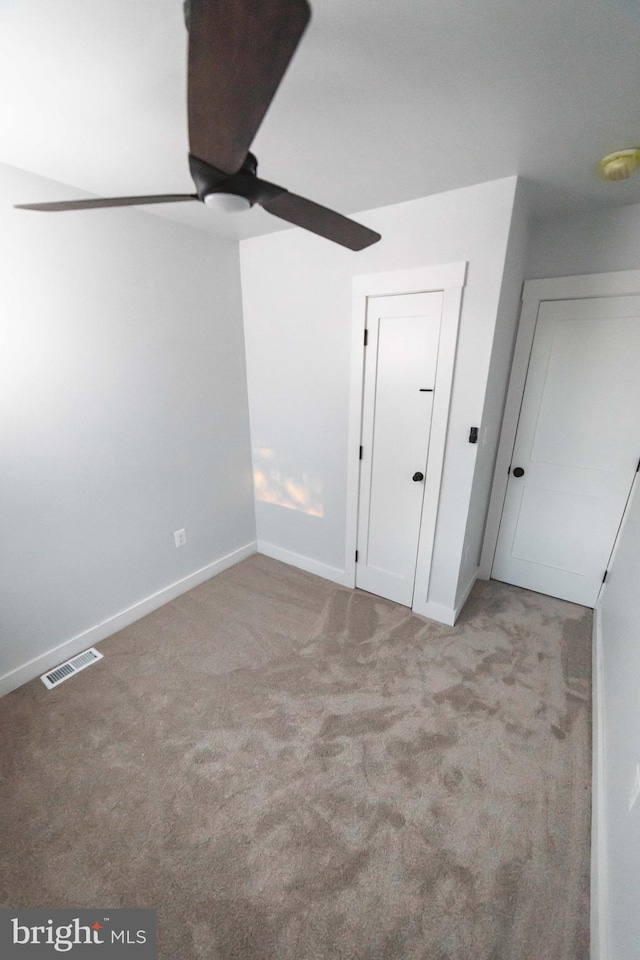 unfurnished bedroom featuring a ceiling fan, carpet, visible vents, and baseboards