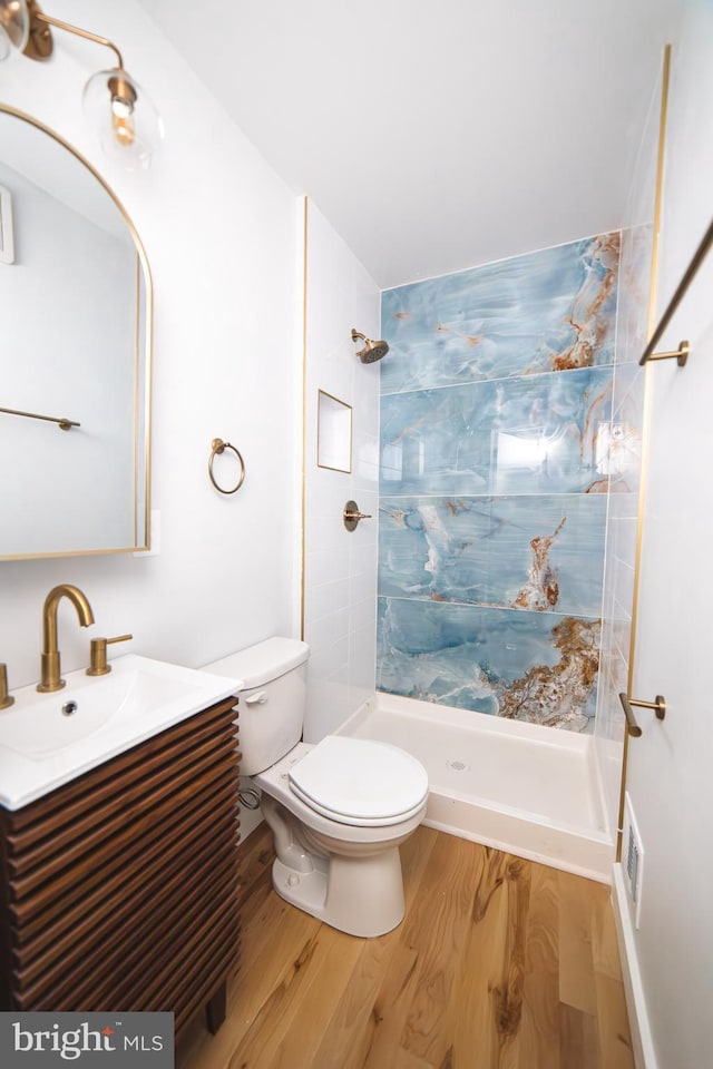 full bathroom with visible vents, toilet, a stall shower, vanity, and wood finished floors