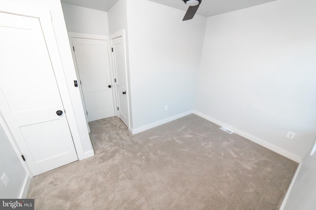 carpeted empty room featuring ceiling fan, visible vents, and baseboards