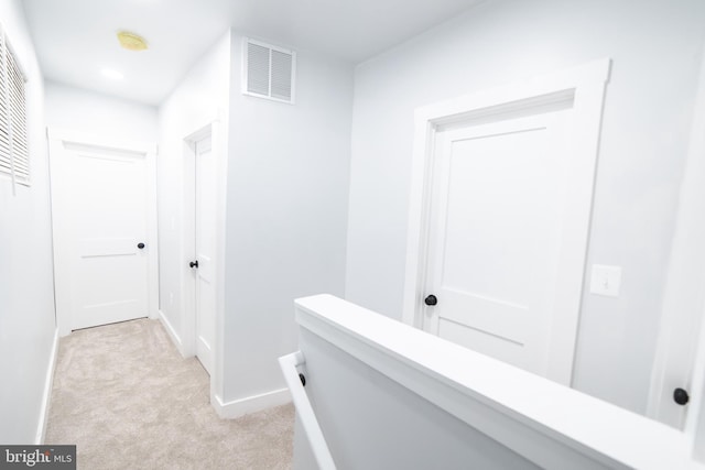 hallway featuring light carpet, baseboards, and visible vents