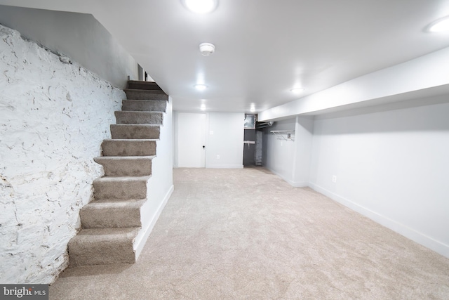 finished basement featuring stairway, carpet, and baseboards