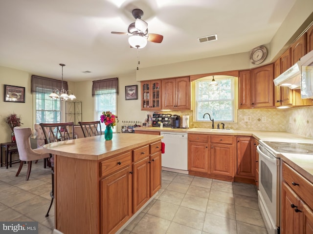 kitchen featuring white appliances, a sink, visible vents, light countertops, and backsplash