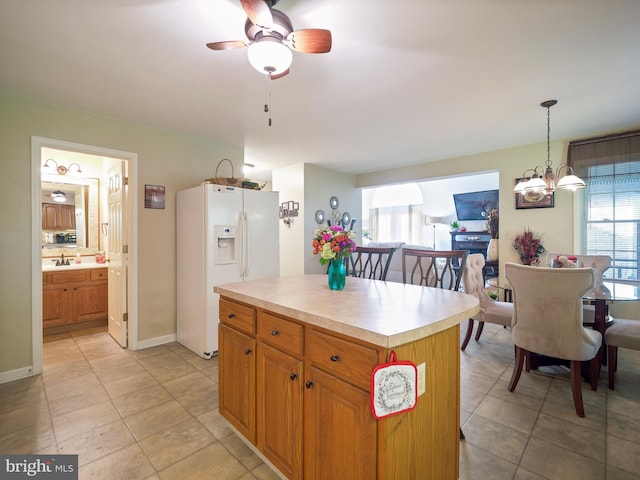 kitchen featuring light tile patterned floors, light countertops, white refrigerator with ice dispenser, and hanging light fixtures