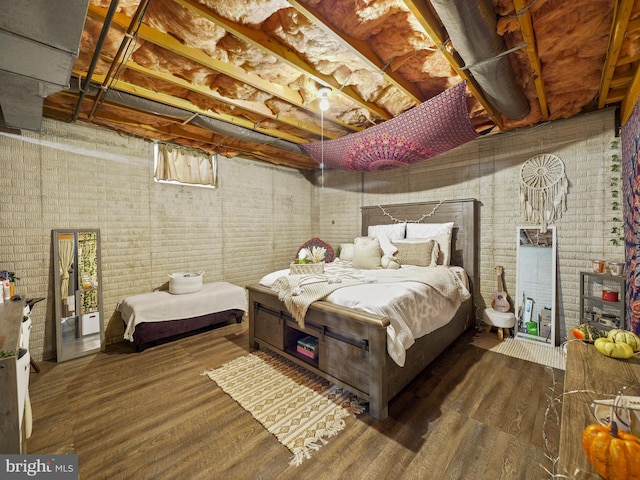 bedroom featuring brick wall and wood finished floors