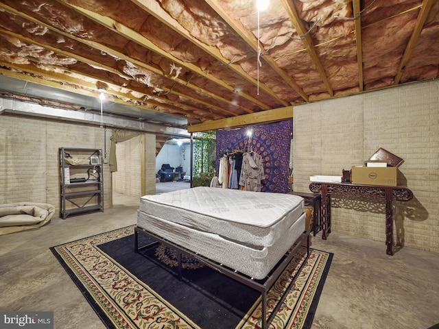 bedroom with brick wall and unfinished concrete floors