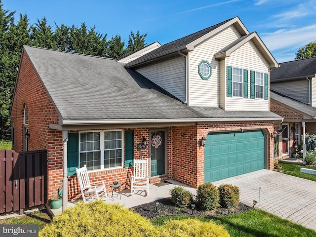 traditional home with driveway, brick siding, an attached garage, and a shingled roof