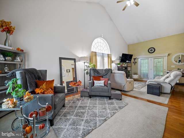 living area with ceiling fan, high vaulted ceiling, and wood finished floors