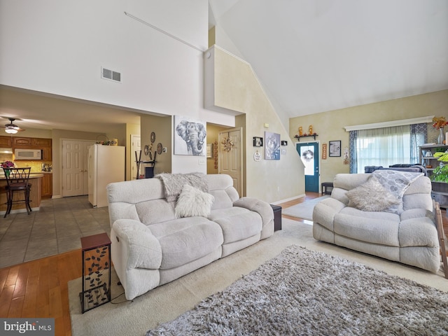 living room with high vaulted ceiling, visible vents, baseboards, and wood finished floors