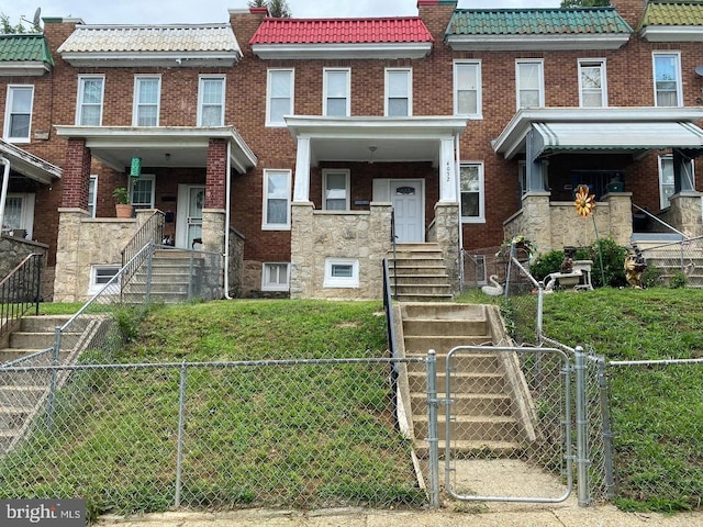 townhome / multi-family property with a tile roof, a gate, fence, and brick siding