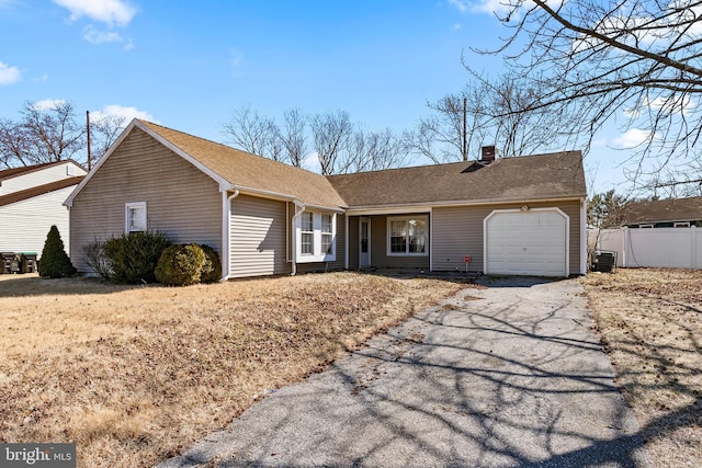 ranch-style home with a garage, a chimney, aphalt driveway, roof with shingles, and fence