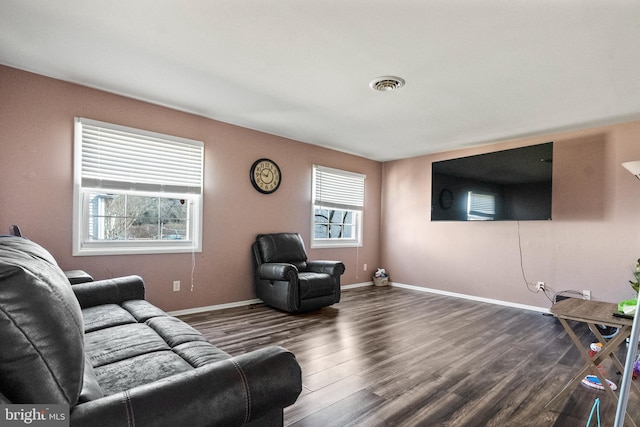 living room featuring dark wood-style flooring, visible vents, and baseboards