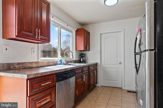 kitchen with reddish brown cabinets, visible vents, stainless steel appliances, a sink, and light tile patterned flooring