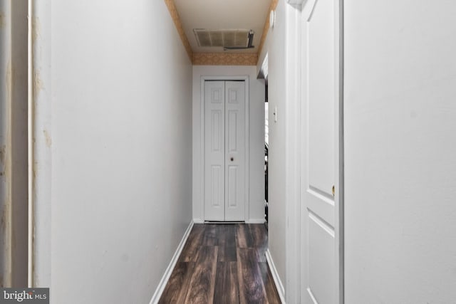 hall with dark wood-type flooring, visible vents, and baseboards