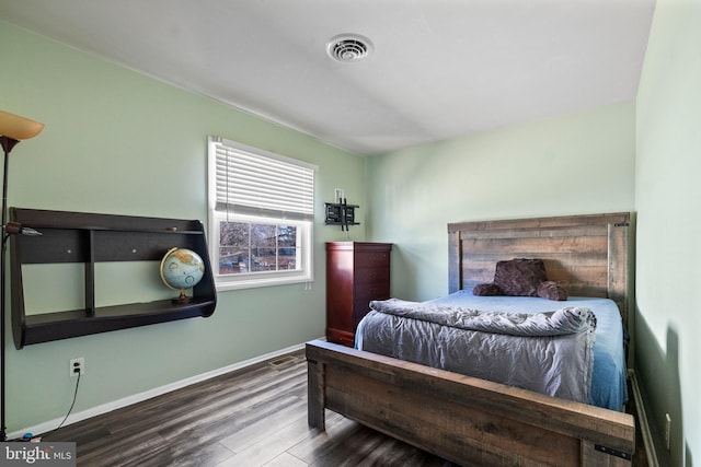 bedroom with wood finished floors, visible vents, and baseboards