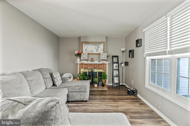 living room featuring a brick fireplace, wood finished floors, and baseboards