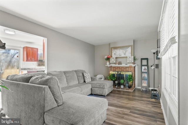 living area with a brick fireplace and dark wood finished floors