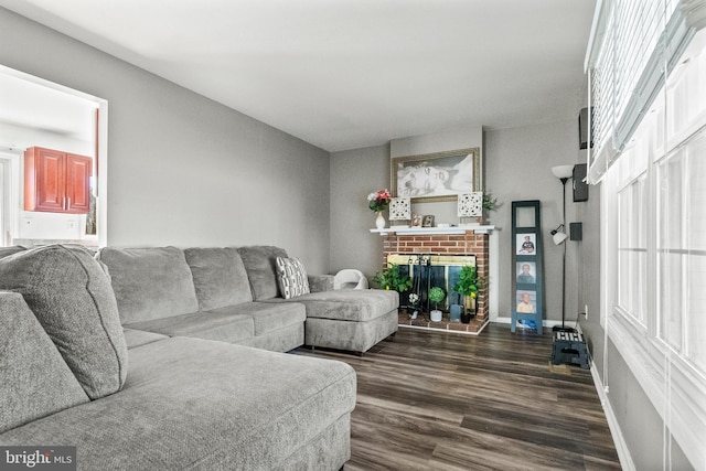 living room featuring dark wood-type flooring, a fireplace, and baseboards